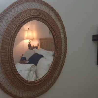 Sale Photo Thumbnail #306: Vintage oval wall mirror with a woven wicker frame, displayed alongside a wooden wall crucifix.