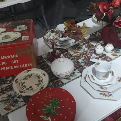 Sale Photo Thumbnail #334: Collection of holiday-themed porcelain tableware, including a boxed Fairfield 16-piece 'Peace on Earth' dinnerware set, octagonal floral plates, and decorative Christmas table linens.