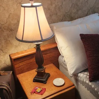Sale Photo Thumbnail #89: Traditional table lamp with a dark wooden baluster base and fabric bell shade, sitting on an oak nightstand next to a bed with decorative pillows.