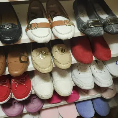Sale Photo Thumbnail #68: Collection of women's shoes arranged on white shelving, including loafers, flats, and casual sneakers from various brands like Michael Kors.