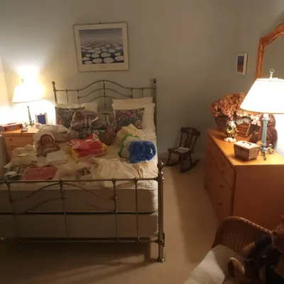 Sale Photo Thumbnail #176: Bedroom set including a brass metal bed frame with mattress, wooden dresser with mirror, nightstand, and various decorative household items.