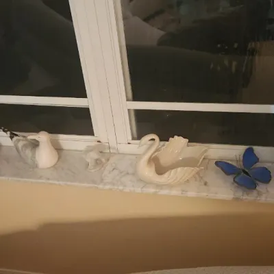 Sale Photo Thumbnail #28: Collection of decorative ceramic and glass items, including a swan Planter, seagull figurine, stained glass butterflies, and assorted vases displayed on a window sill.