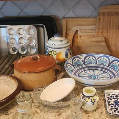 Sale Photo Thumbnail #224: Assortment of rustic and hand-painted kitchenware, including terra cotta casseroles, ceramic bowls, serving platters, and bakeware.