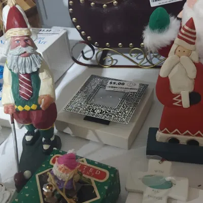 Sale Photo Thumbnail #340: Collection of Christmas decorations and folk art figures, including hand-carved Santa clauses, a plush singing Santa, Metropolitan Museum of Art ornaments, and a silver-tone frame.