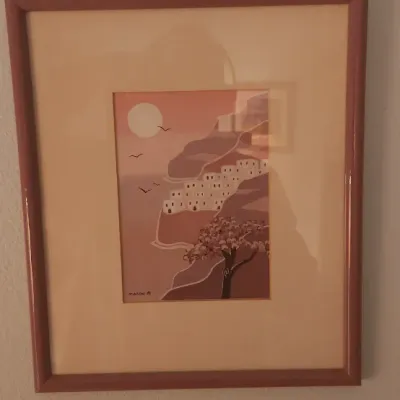 Sale Photo Thumbnail #172: Framed signed art print depicting a Mediterranean coastal village at sunset, rendered in warm mauve and terracotta tones.