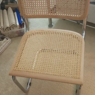 Sale Photo Thumbnail #197: Cesca-style cantilever dining chair featuring tubular chrome framing, light wood trim, and woven cane seat and backrest panels.