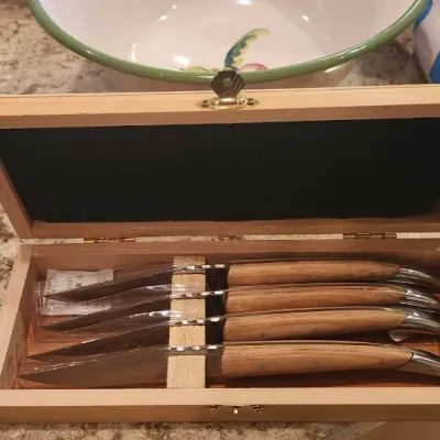 Sale Photo Thumbnail #235: Set of four Laguiole-style steak knives with natural wood handles, presented in an open fitted wooden storage box.