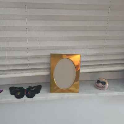 Sale Photo Thumbnail #186: A collection of windowsill decor, including metallic picture frames, a glittery masquerade mask, a black butterfly accessory, and small figurines.
