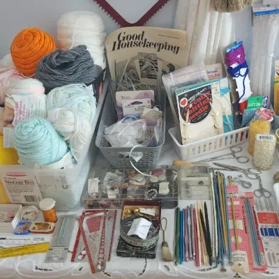 Sale Photo Thumbnail #187: Large assortment of crafting supplies, including knitting needles, crochet hooks, colorful yarn skeins, spools of thread, sewing notions, and a vintage stuffed dog in a safari outfit.