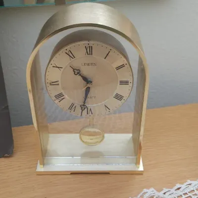 Sale Photo Thumbnail #303: Vintage Linden brass and glass arched mantel clock with a swinging pendulum and Roman numeral dial.