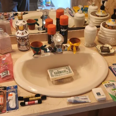 Sale Photo Thumbnail #118: Assorted bathroom toiletries, lotion dispensers, dental hygiene products, and shoelaces arranged on a sink vanity.