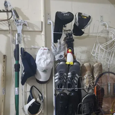 Sale Photo Thumbnail #344: Assortment of garden tools, golf accessories, shoes, and tennis racquets organized on wall mounts in a garage setting.