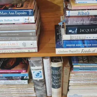 Sale Photo Thumbnail #212: Wooden bookcase filled with stacks of vintage cookbooks, focusing heavily on Italian cuisine and general household recipes.