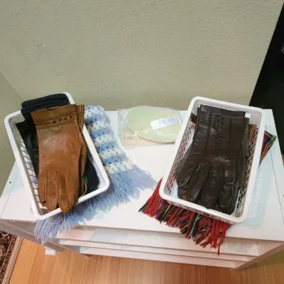 Sale Photo Thumbnail #51: Collection of vintage leather dress gloves, knit scarves, and cold-weather accessories presented in white plastic storage baskets.