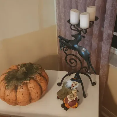 Sale Photo Thumbnail #29: Seasonal decor items including a large ceramic pumpkin, a witch figurine, and a dark metal leaping deer candelabra holding white pillar candles.