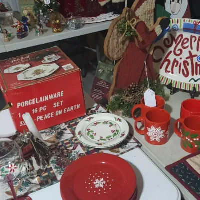 Sale Photo Thumbnail #332: Collection of Christmas decorations and tableware including a boxed 16-piece Fairfield porcelain set, red festive mugs, holiday plates, and an angel figurine.