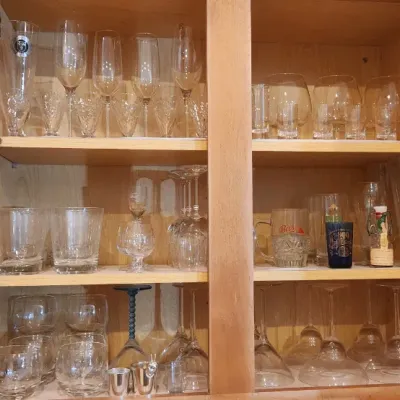 Sale Photo Thumbnail #227: Collection of assorted glassware, stemware, and barware arranged inside a wooden kitchen cabinet.