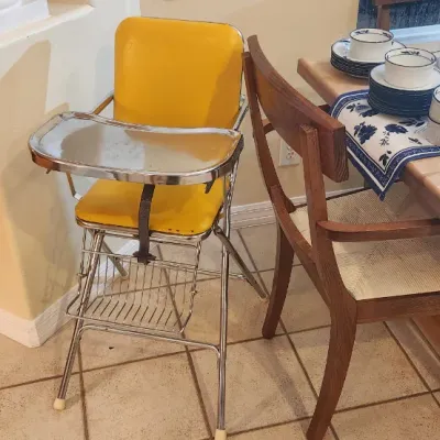 Sale Photo Thumbnail #239: Vintage mid-century high chair featuring yellow vinyl upholstery and a chrome frame with attached tray.