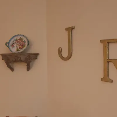 Sale Photo Thumbnail #10: Gold-tone metal wall letters 'J' and 'R' alongside a small carved wall bracket shelf displaying a floral decorative plate.