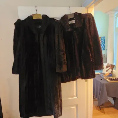 Sale Photo Thumbnail #92: Two dark vintage fur coats hanging from a doorframe, including a full-length coat and a jacket-length coat.