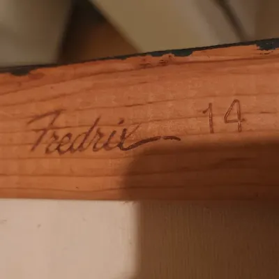 Sale Photo Thumbnail #134: Close-up detail of a wooden canvas stretcher bar stamped with the Fredrix brand name and size 14.