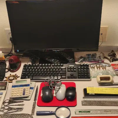 Sale Photo Thumbnail #259: A collection of office electronics and desk supplies, including a Samsung monitor, Dell keyboard, various calculators, computer mice, rulers, scissors, and a slide rule.