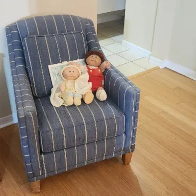 Sale Photo Thumbnail #168: Blue striped upholstered armchair with wooden legs, holding two vintage Cabbage Patch Kids dolls.