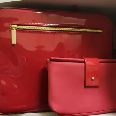 Sale Photo Thumbnail #64: Red patent leather travel case with gold-tone zippered pocket alongside a matching small clutch or pouch.