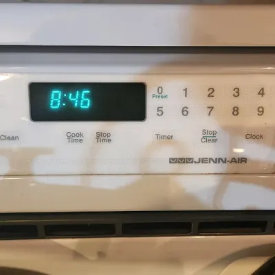 Sale Photo Thumbnail #222: Jenn-Air white electric oven control panel featuring a digital clock display and touch pad settings.
