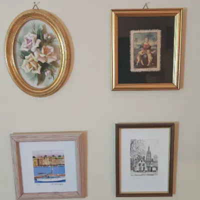 Sale Photo Thumbnail #23: Collection of four wall art pieces including a 3D floral ceramic in an oval gilt frame, a framed tapestry print, a harbor scene watercolor, and a black-and-white architectural etching.
