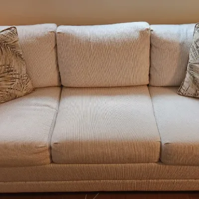 Sale Photo Thumbnail #261: Contemporary light beige upholstered three-cushion sofa paired with two tropical palm leaf throw pillows.