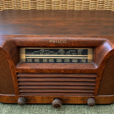 Sale Photo Thumbnail #51: Vintage Philco tabletop tube radio featuring a polished wood cabinet with a multi-band tuning dial and lower control knobs.