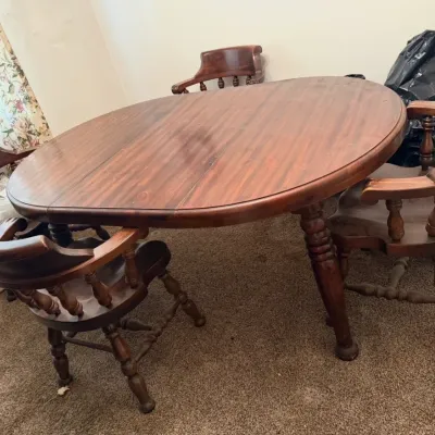 Sale Photo Thumbnail #17: Vintage dark wood oval dining table with turned legs, accompanied by matching captain's chairs featuring spindle backs.