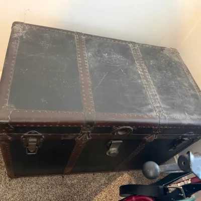 Sale Photo Thumbnail #26: Antique steamer trunk featuring dark canvas exterior trim with metal latches and stud detailing.