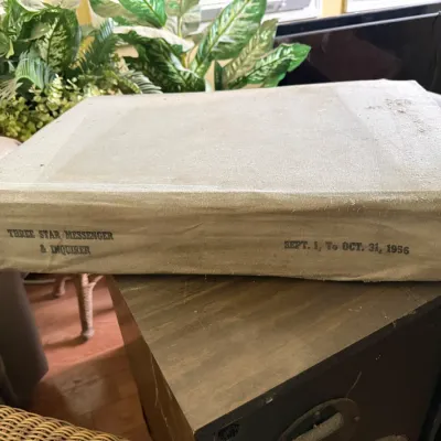 Sale Photo Thumbnail #34: Bound volume of the Three Star Messenger & Inquirer newspaper, covering Sept. 1 to Oct. 31, 1956. The large canvas-bound book shows light age-related wear along the spine and edges.