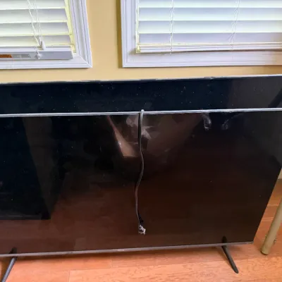 Sale Photo Thumbnail #36: Two modern flat-screen televisions stacked together, including one with small stand legs and a power cord dangling over the front screen.