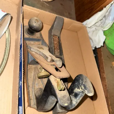 Sale Photo Thumbnail #45: Vintage hand plane woodworking tools resting in a cardboard box, showing heavy wear and surface rust.
