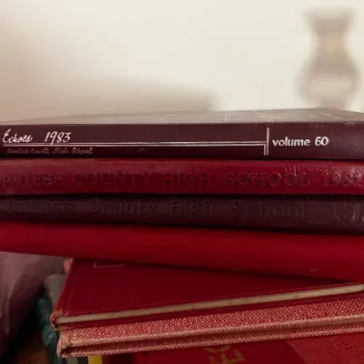 Sale Photo Thumbnail #24: Stack of Daviess County High School yearbooks including Echoes 1983 Volume 60 and additional red hardbound editions.