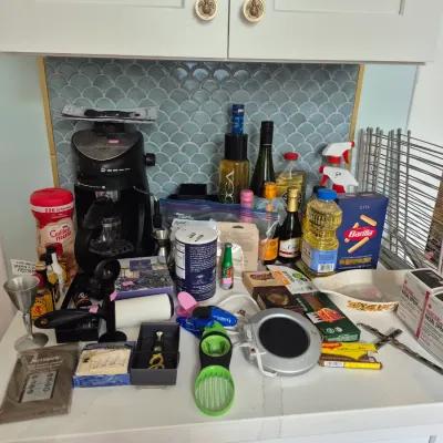 Sale Photo Thumbnail #13: Assortment of household items, kitchen gadgets, pantry goods, and small appliances arranged on a countertop.