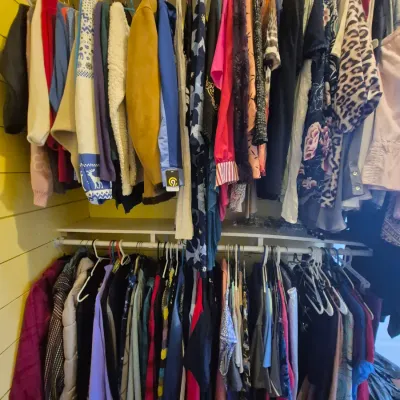 Sale Photo Thumbnail #87: Two-tier closet rod filled with an assortment of women's clothing, including jackets, sweaters, tops, and dresses in various colors and patterns.