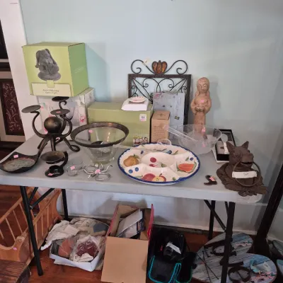 Sale Photo Thumbnail #33: Folding table displays various home decor items, including a fruit-patterned serving tray, wrought-iron candelabras, glass bowls, and a horse head door knocker.