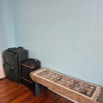 Sale Photo Thumbnail #67: Rustic wooden bench topped with a patterned runner rug, alongside two modern rolling suitcases.