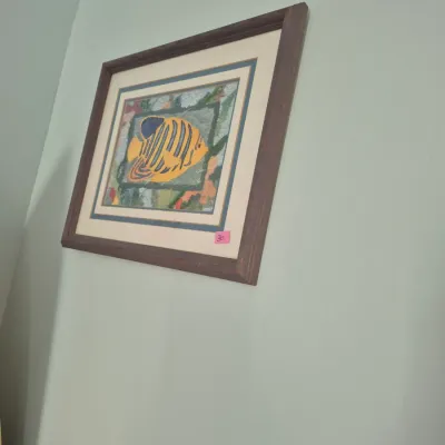 Sale Photo Thumbnail #53: Framed textile art piece depicting a yellow and black tropical fish, presented in a dark wood frame with layered matting.