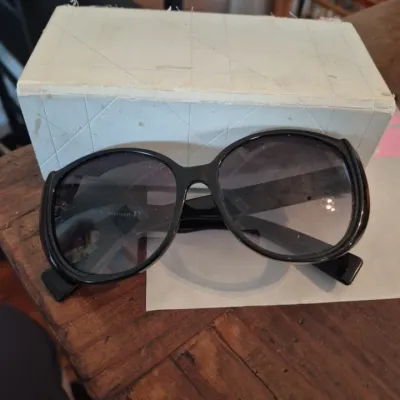Sale Photo Thumbnail #12: Vintage Christian Dior black oversized sunglasses with dark lenses, displayed alongside their original quilted white hard case.