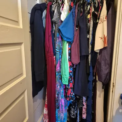 Sale Photo Thumbnail #86: A closet filled with various hung women's clothing, including dresses, blouses, and outerwear.
