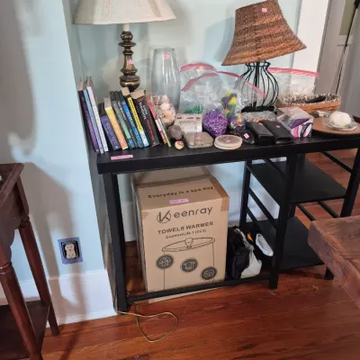 Sale Photo Thumbnail #47: Black console table featuring tabletop lamps, books, crafting supplies, and a boxed Keenray towel warmer stored underneath.