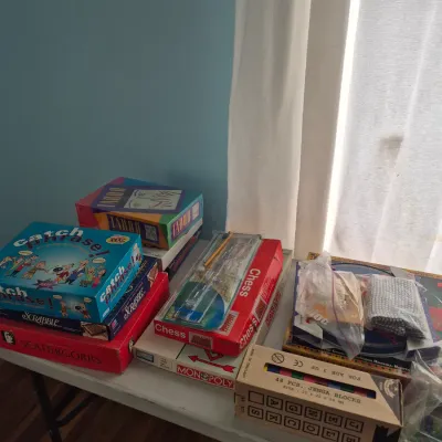 Sale Photo Thumbnail #104: Collection of classic board games displayed on a table, including Catch Phrase, Taboo, Scrabble, Monopoly, Chess, and Scattergories.