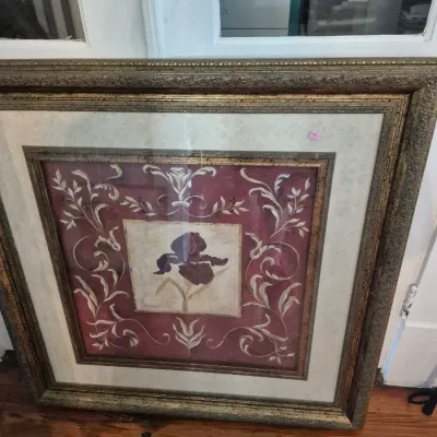 Sale Photo Thumbnail #60: Framed botanical wall art featuring a purple iris center surrounded by scrollwork details, housed in a heavy gilded metallic frame.