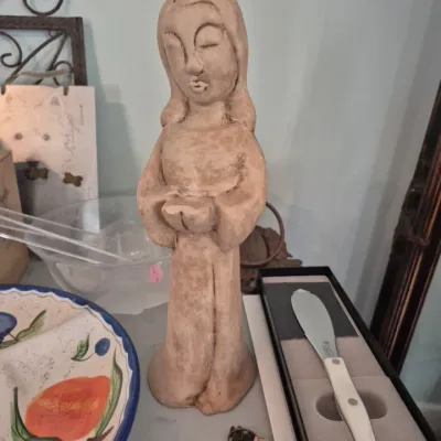 Sale Photo Thumbnail #3: Hand-carved terracotta or clay statue of a praying female figure, displayed alongside a boxed Cutco spreader knife and ceramic serving dish.