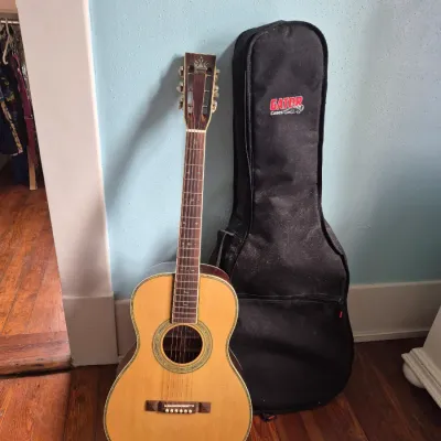 Sale Photo Thumbnail #116: Vintage acoustic parlor guitar with slotted headstock and pearloid trim, shown alongside a black Gator Cases soft gig bag.